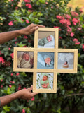 Hand holding a wooden photo frame collage with baby pictures, outdoor garden background